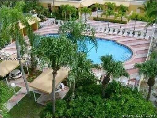 In-ground swimming pool with integrated stairs, surrounded by a paved patio, covered cabana structures, and mature palm trees