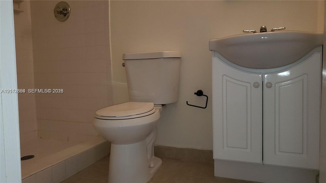 Bathroom featuring a vanity cabinet with a curved basin, a white toilet, and a tiled shower stall