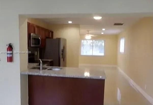 Kitchen featuring wood-finish cabinetry, stone-surface breakfast bar, recessed lighting, and stainless steel appliances