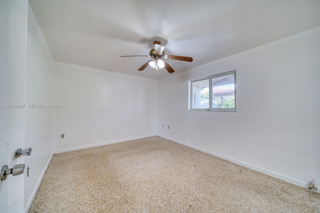 Room featuring neutral wall finishes, carpeting, a ceiling-mounted light fixture with a fan, and a single-pane sliding window