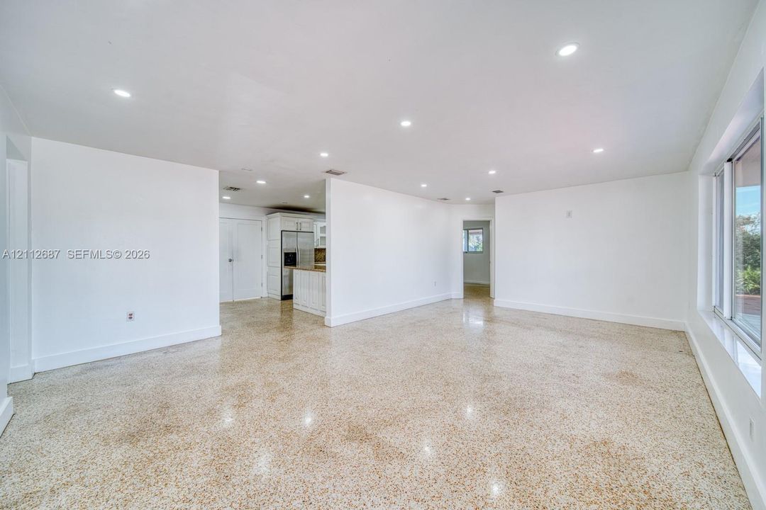 Open-concept interior featuring polished aggregate flooring, recessed lighting, and large-format sliding windows