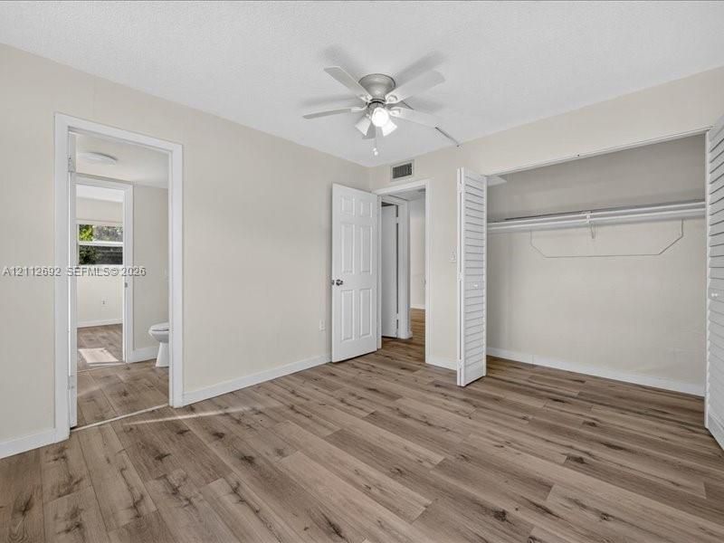 Room featuring wood-finish flooring, a ceiling fan with integrated lighting, and a closet with bifold louvered doors