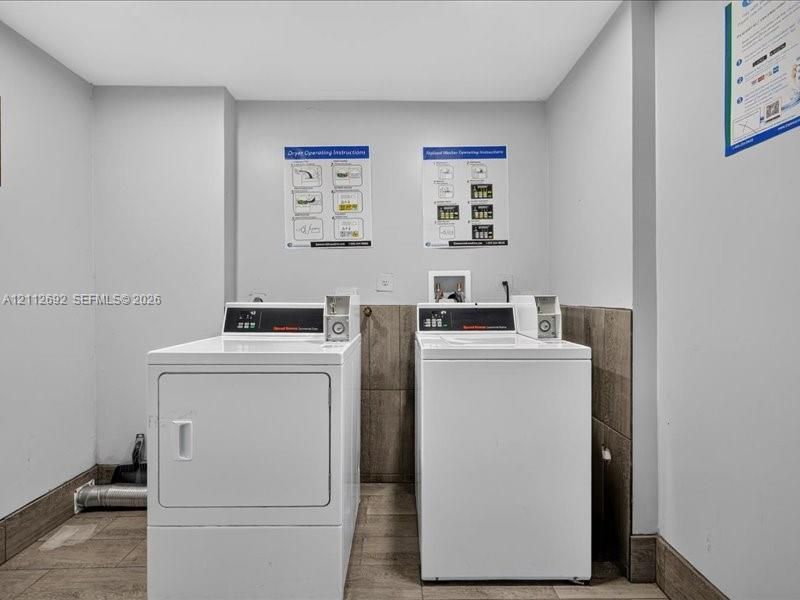 Laundry area featuring dual top-loading washer and front-loading dryer units, tile flooring, and half-height wall tiling