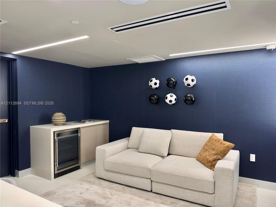 Built-in cabinetry with integrated under-counter beverage refrigerator, recessed linear lighting, and ceiling-mounted HVAC system