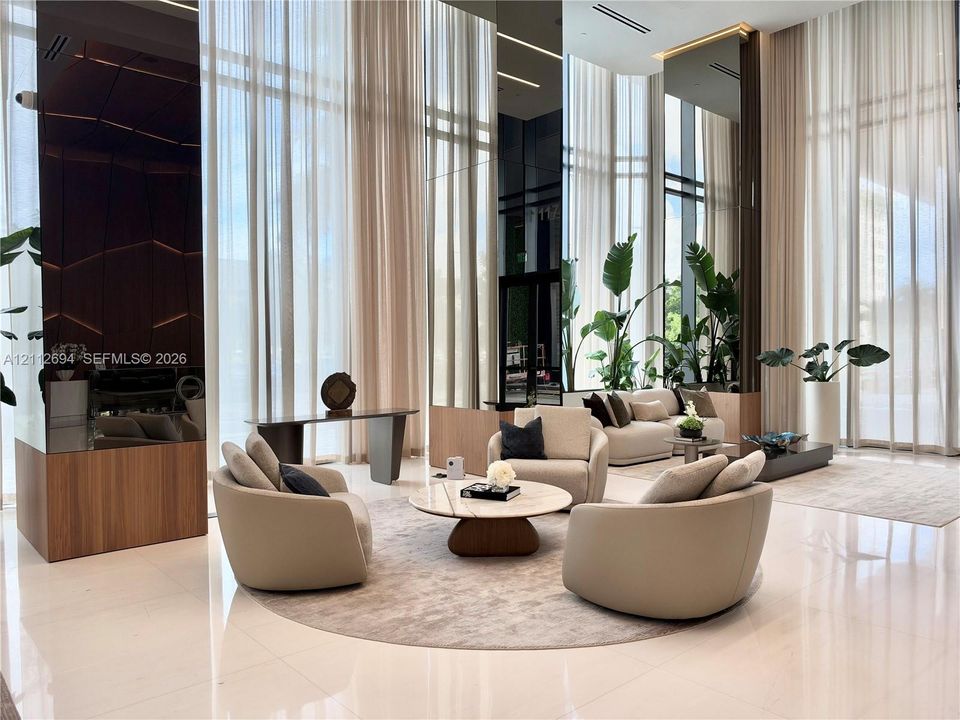 Double-height floor-to-ceiling windows, polished stone flooring, integrated floor-to-ceiling mirror paneling, and wood-finish architectural column cladding