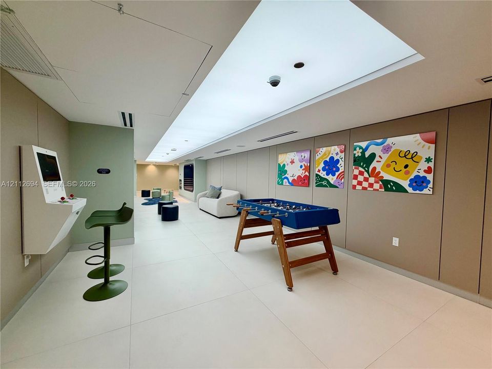 Large-format tile flooring, recessed linear lighting, and wall-mounted multimedia station