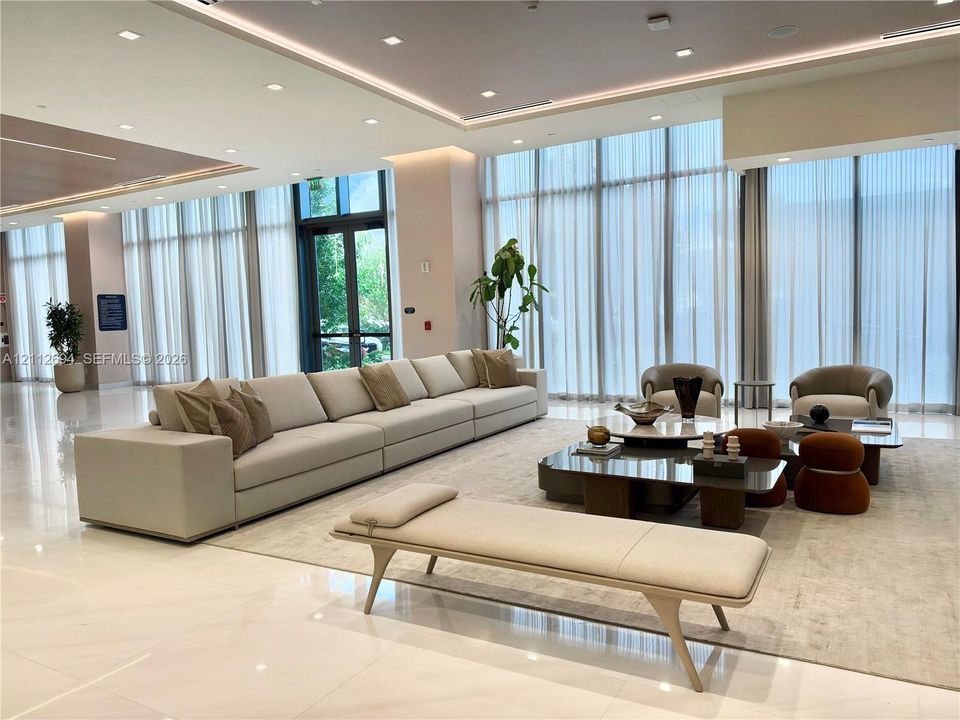 Expansive common area featuring floor-to-ceiling windows, polished tile flooring, recessed cove lighting, and drop ceiling details