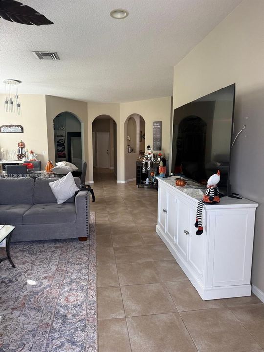 Open-concept interior featuring large-format neutral tile flooring and distinctive arched architectural entryways