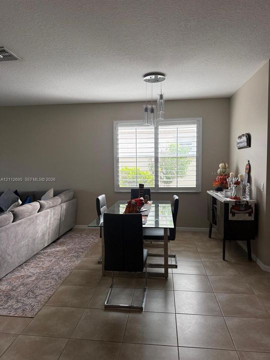 Ceramic tile flooring, multi-pane window with plantation shutters, and a three-light glass pendant fixture