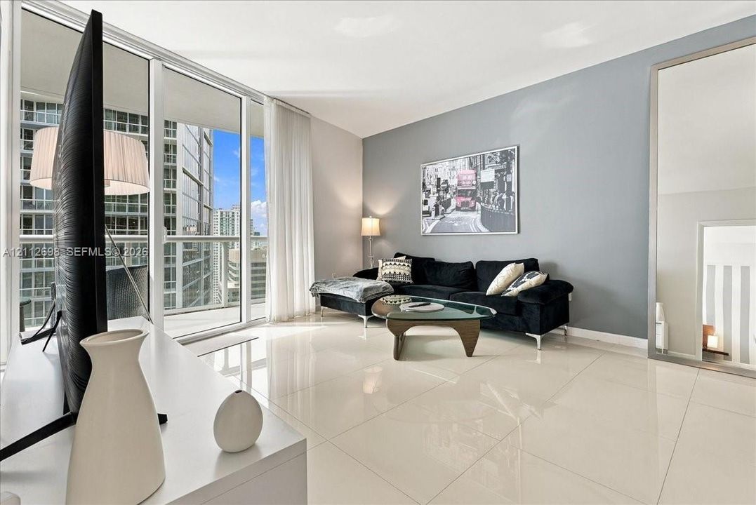 Floor-to-ceiling glass windows, full-height sliding glass balcony door, polished tile flooring, and neutral wall tones