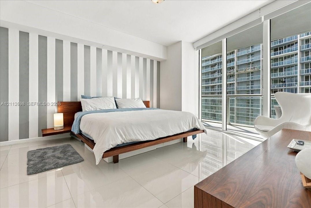 Floor-to-ceiling windows, polished tile flooring, and integrated wall-mounted bedside shelving