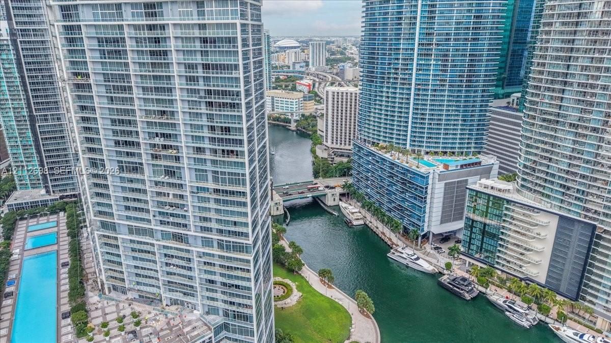 High-rise residential tower featuring floor-to-ceiling glass windows, private balconies, and proximity to a waterway with boat slips and a swimming pool