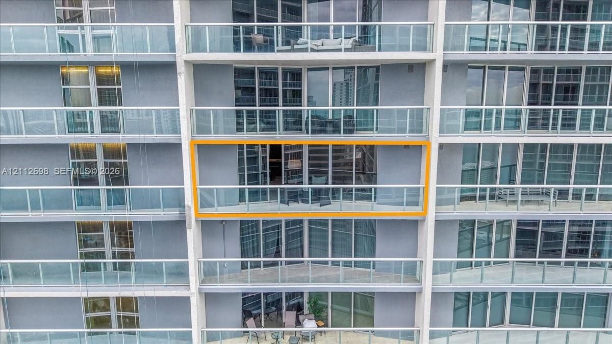 High-rise exterior featuring floor-to-ceiling glass paneling and a private balcony with metal railings