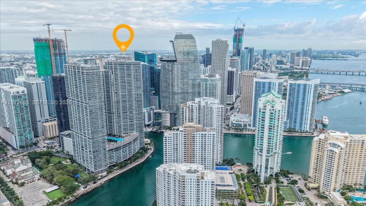 High-rise residential tower featuring a glass-facade exterior and a podium-level swimming pool, situated within a dense urban waterfront landscape