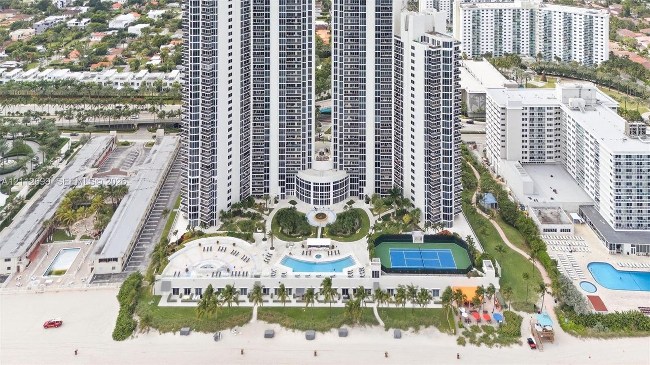 High-rise residential tower featuring a direct beachfront location, swimming pool with surrounding deck, tennis court, and professionally landscaped grounds