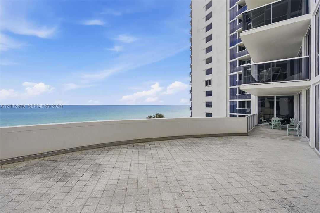 Expansive Oceanfront terrace featuring tiled flooring, a solid perimeter wall, and direct ocean exposure and breathtaking Sunrise views.