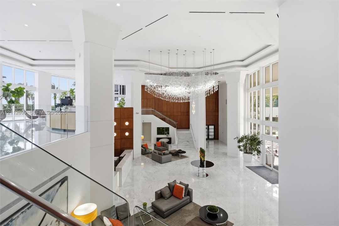 Grand atrium featuring high ceilings, stone flooring, a multi-tiered crystal chandelier, expansive floor-to-ceiling windows, and wood-paneled walls