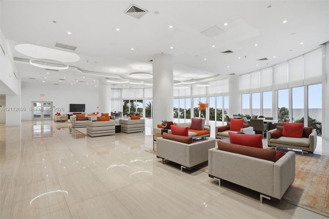 Expansive open-concept space featuring polished tile flooring, floor-to-ceiling windows, recessed lighting, and integrated circular light fixtures