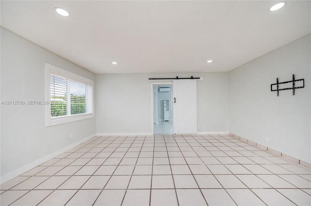 Interior space featuring ceramic tile flooring, recessed lighting, a sliding barn-style door, and a dual-pane window with white trim