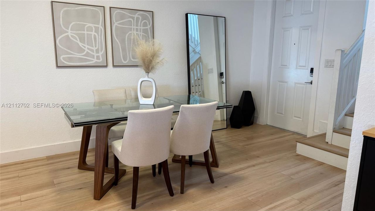 Interior space featuring wood-finish flooring, a paneled entry door, and a white staircase with a wooden handrail