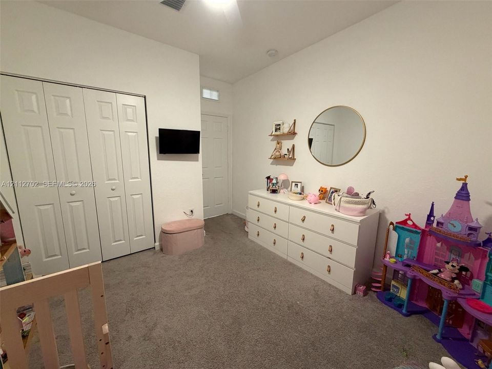 Neutral-toned interior space featuring carpeted flooring, high ceilings, and double-door closet cabinetry