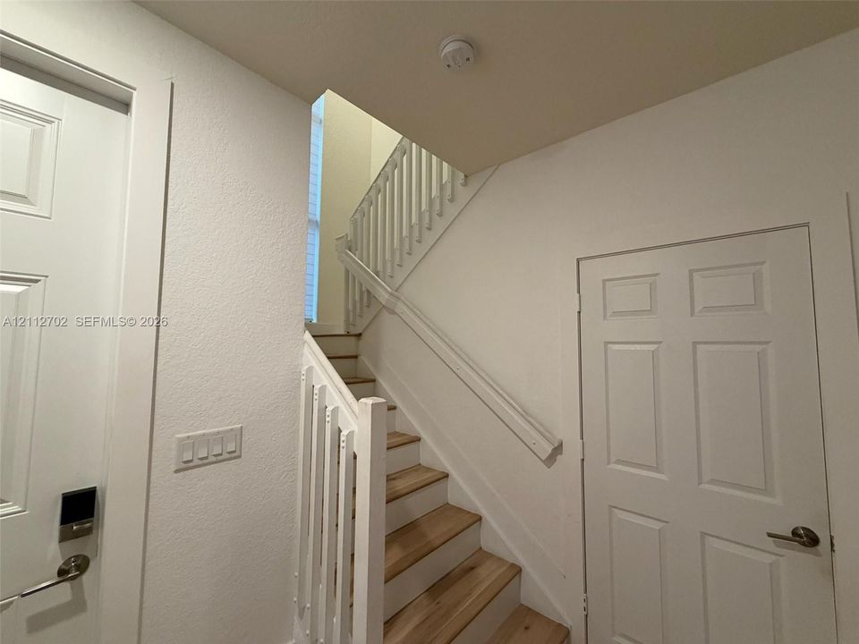 Staircase featuring wood-finish treads, white painted risers, and a white balustrade with a coordinating handrail