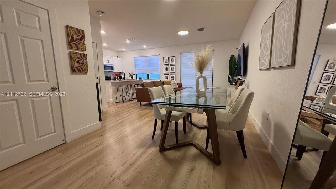 Open-concept interior featuring light-toned wood-finish flooring, recessed lighting, and kitchen cabinetry with a built-in island