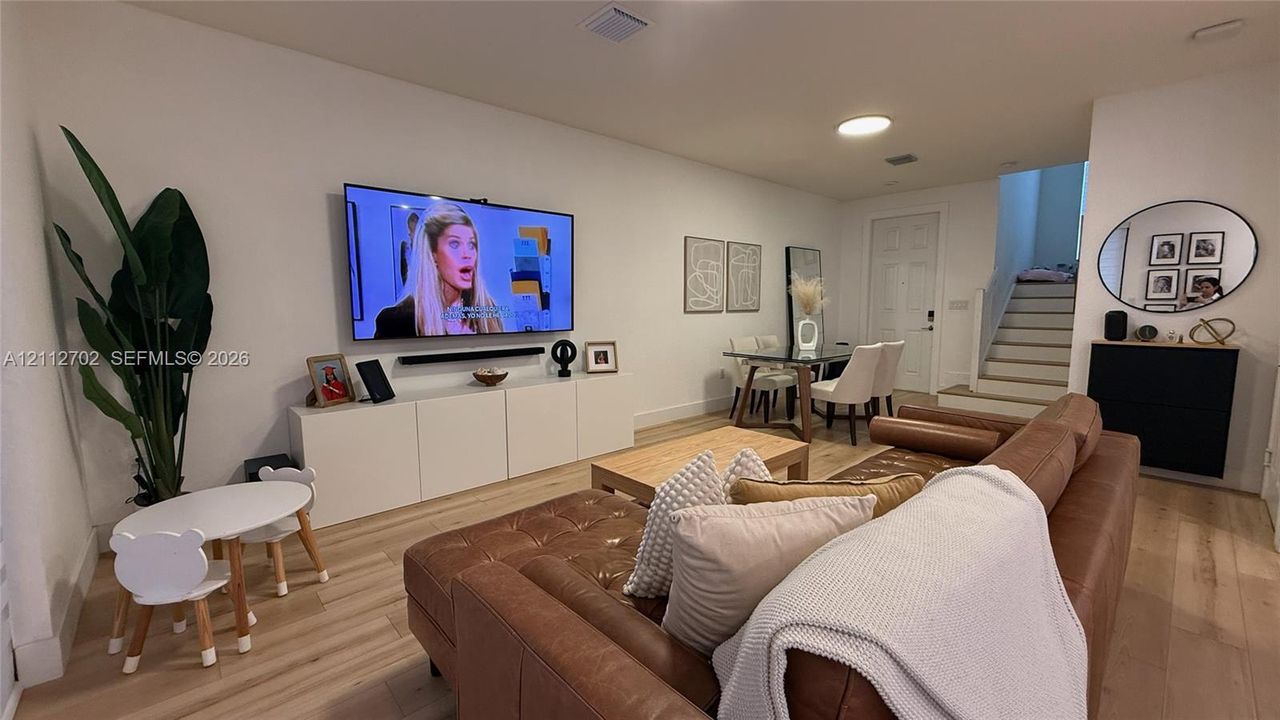 Open-concept interior featuring wood-finish flooring, flush-mount ceiling lighting, and a staircase with painted risers