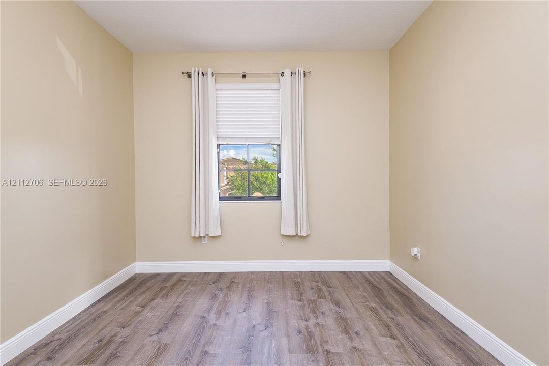 Room featuring wood-finish flooring, neutral wall paint, and a single-pane window with grid detailing