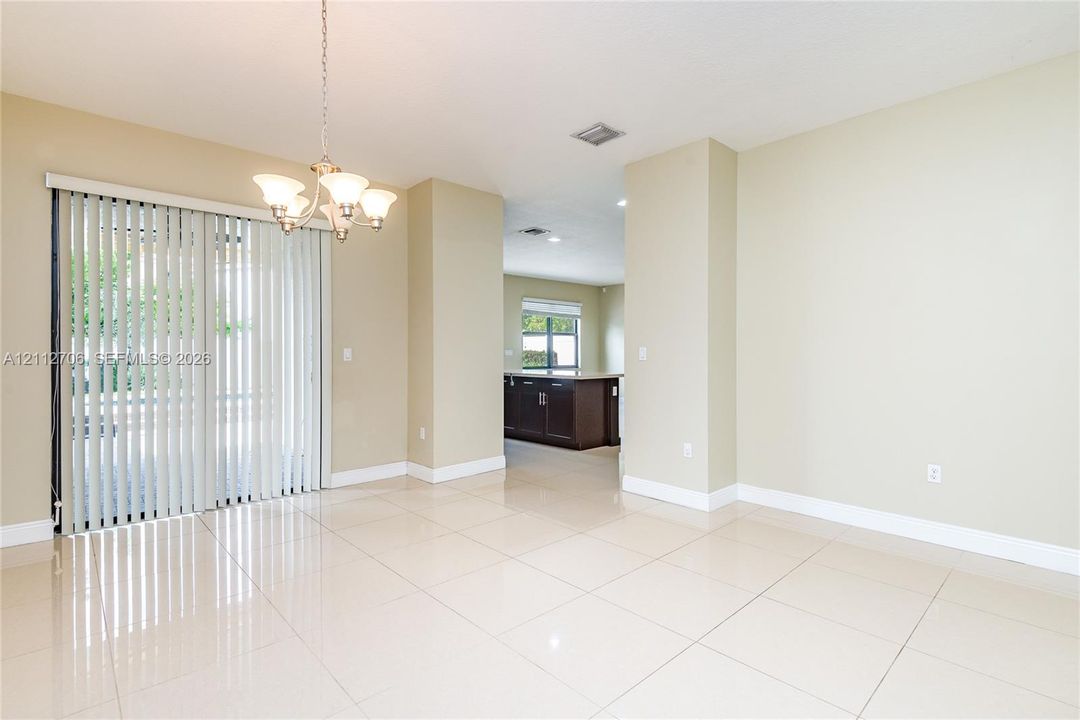 Open interior space featuring polished tile flooring, a multi-arm chandelier, and sliding glass doors