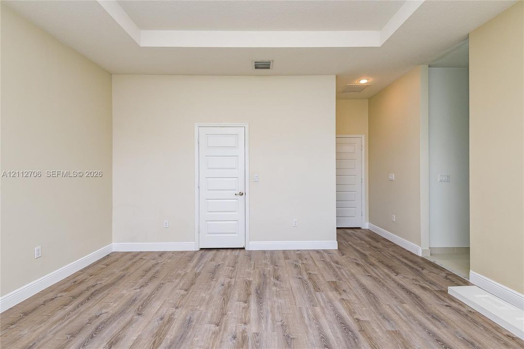Interior space featuring a recessed tray ceiling, neutral wall tones, and wood-finish flooring