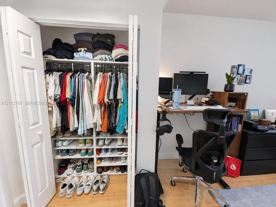 Bi-fold closet doors featuring a multi-tier organizational system with custom shelving and hanging rods over wood-finish flooring