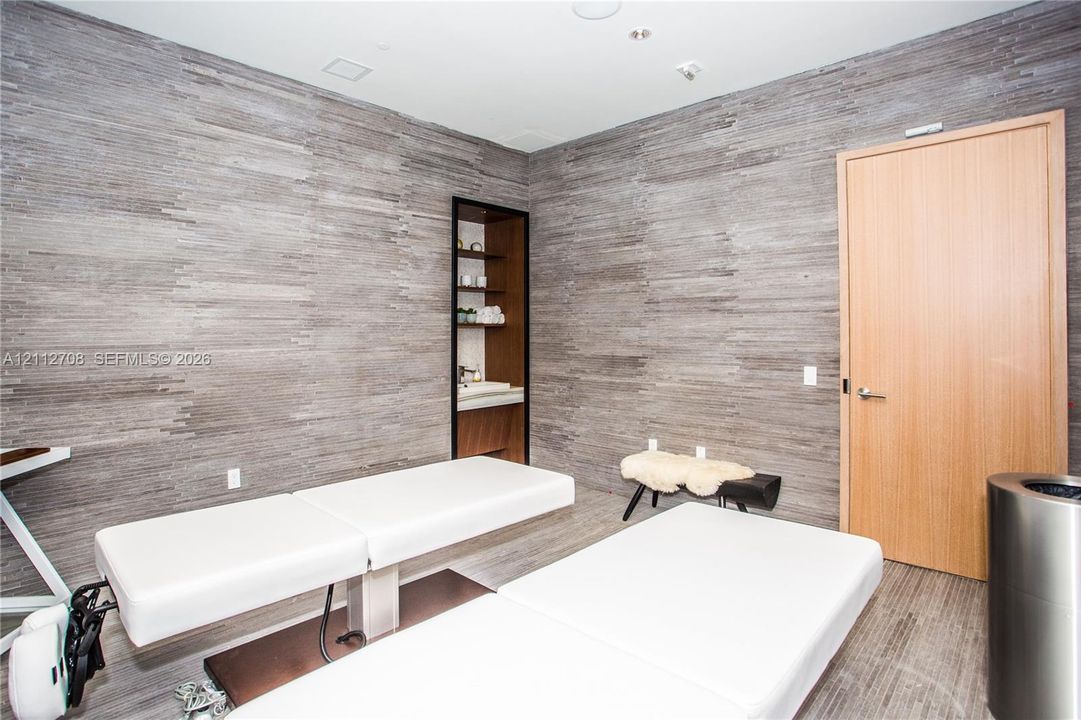 Textured stone-finish wall cladding, recessed shelving with integrated lighting, wood-finish door, and integrated ceiling lighting