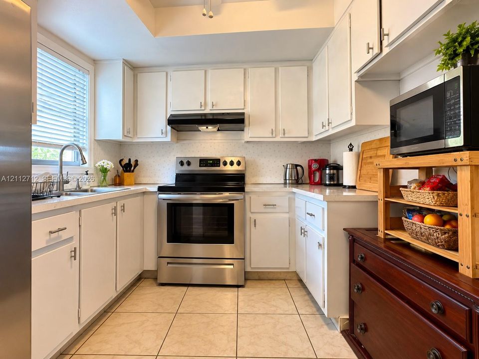 Kitchen featuring white cabinetry, solid-surface countertops, stainless steel range, and tile flooring