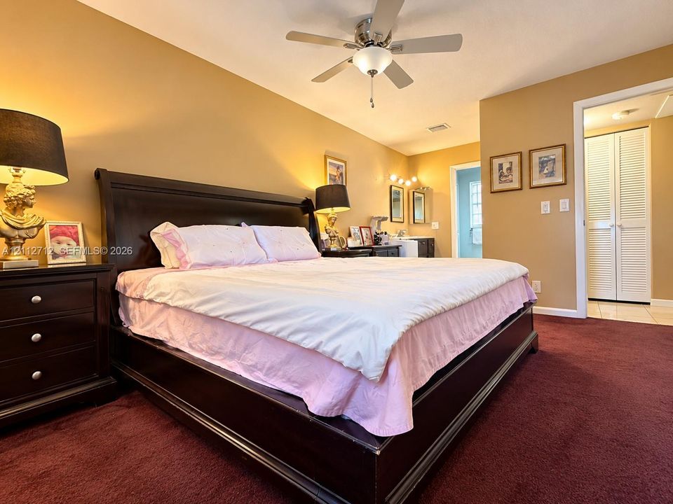 Bedroom featuring carpeted flooring, ceiling fan with integrated light fixture, and closet with louvered doors