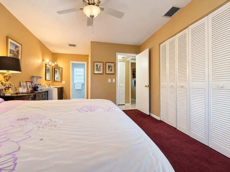 Wall-to-wall carpeting, ceiling fan with integrated lighting, and white louvered-style closet doors