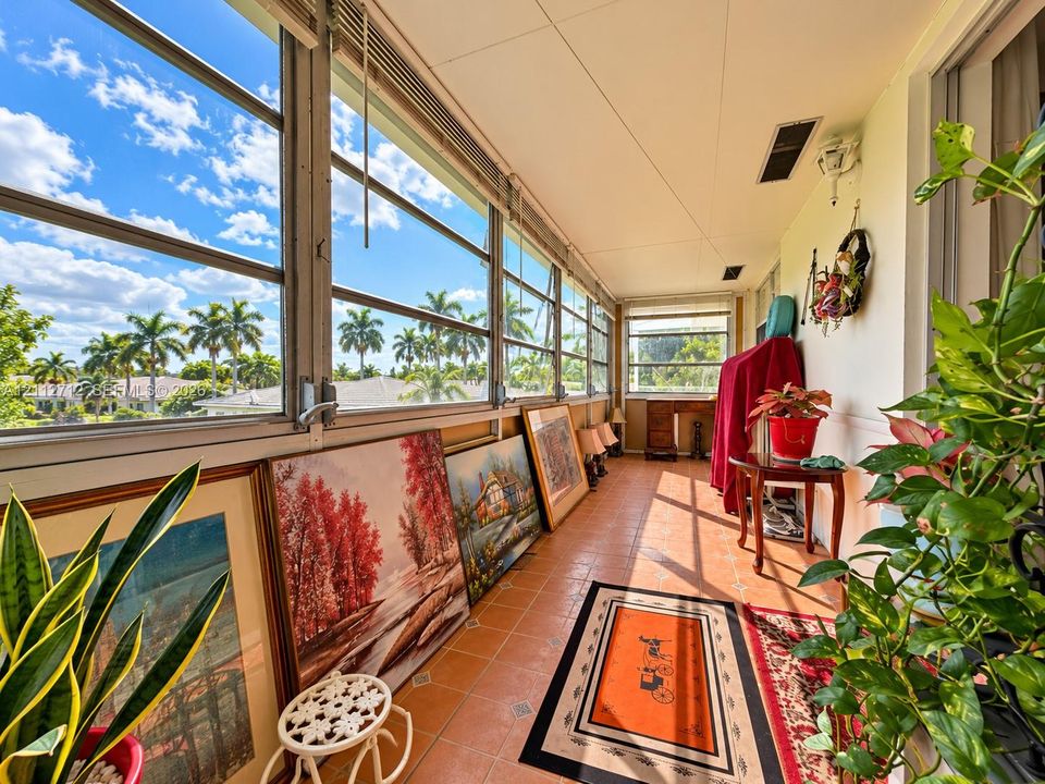 Enclosed sunroom featuring expansive windows with sliding panels, ceramic tile flooring, and integrated ceiling lighting