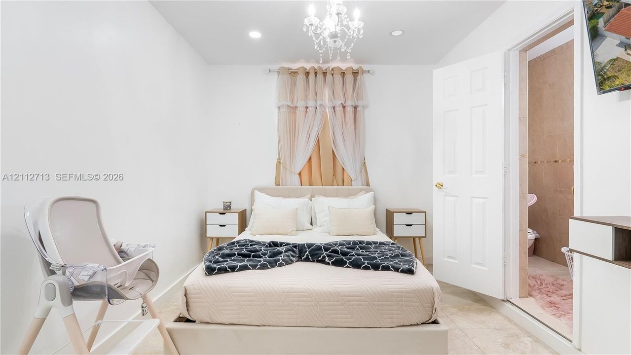Interior space featuring neutral tile flooring, recessed lighting, and a multi-tiered crystal chandelier