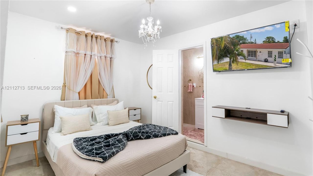 Neutral-tone tile flooring, crystal-style chandelier light fixture, recessed ceiling lighting, and six-panel interior door