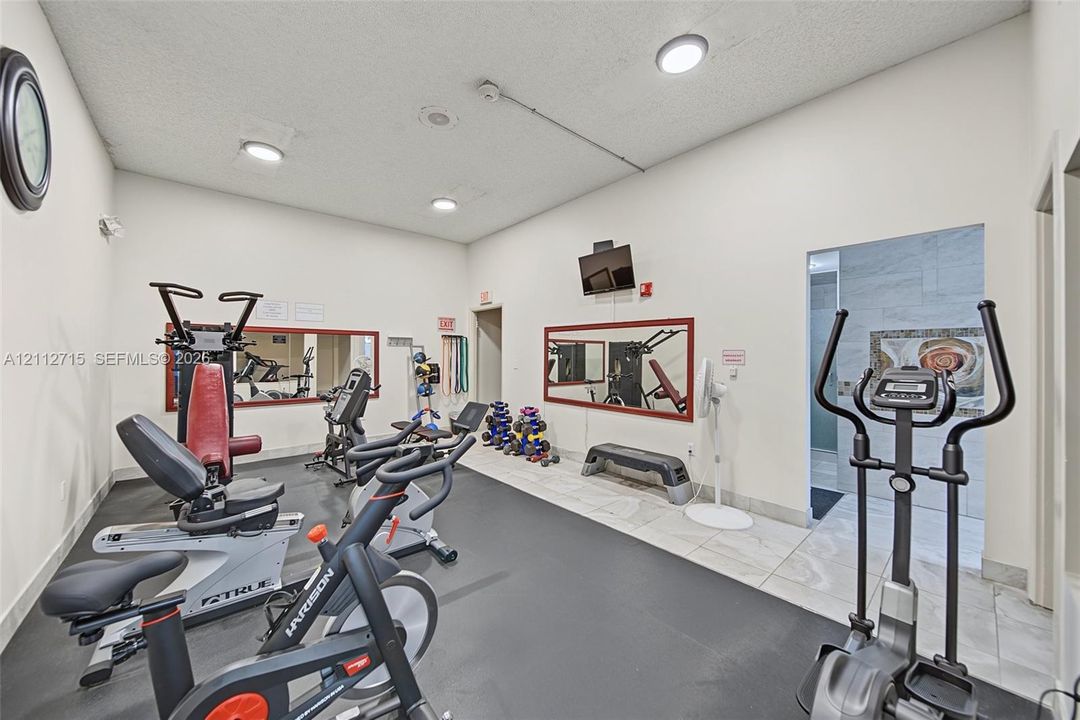 Fitness center featuring high ceilings, wall-mounted mirrors, recessed lighting, and durable rubberized flooring