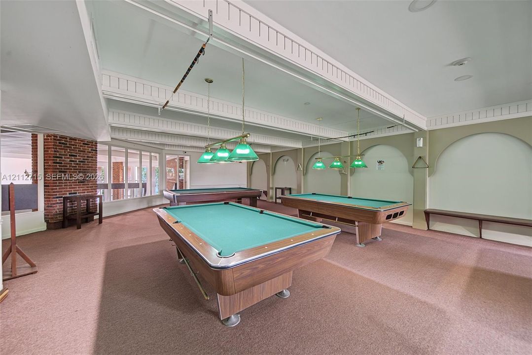 Expansive room featuring exposed brick architectural detailing, recessed arched wall niches, coffered ceilings, and multiple tiered pendant light fixtures