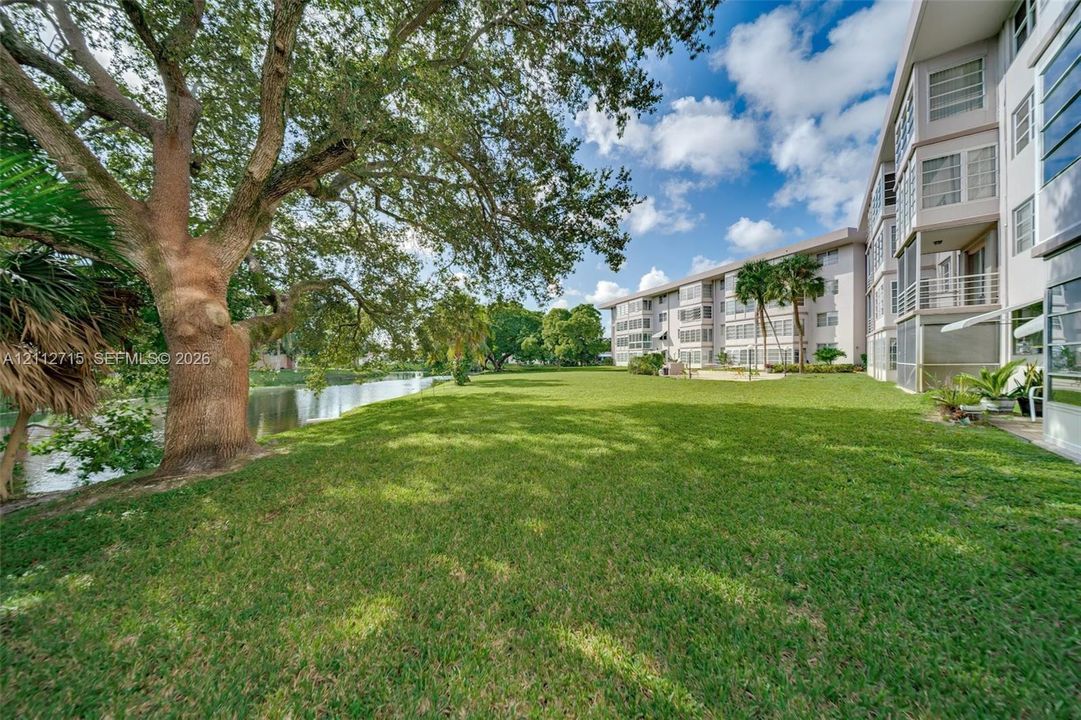 Expansive green space featuring mature trees, waterfront exposure, and multi-story building exterior with private balconies