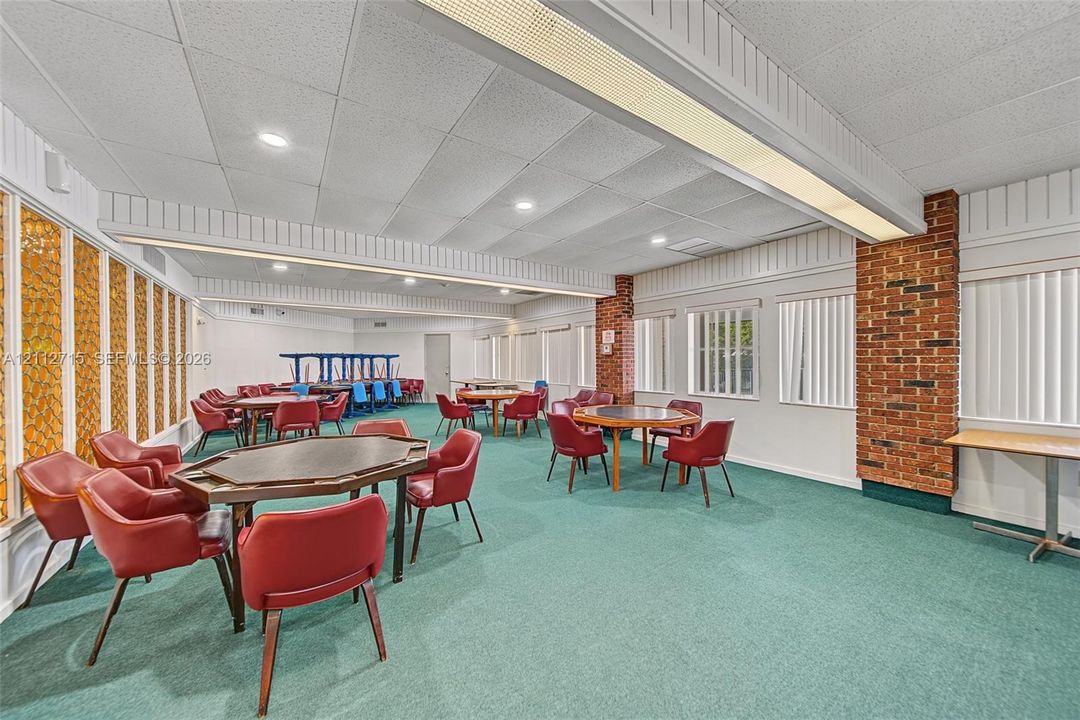 Expansive interior space featuring a brick pillar, textured ceiling with recessed lighting, integrated track lighting, and vertical window blinds