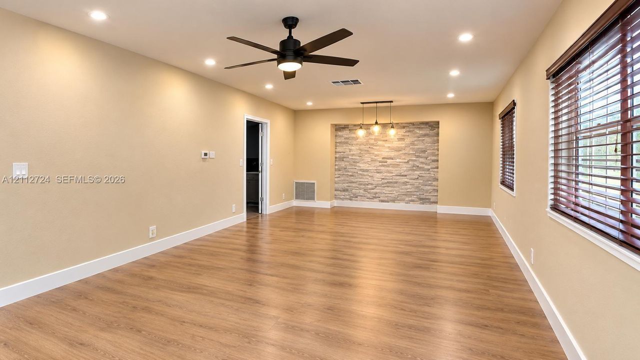 Interior space featuring wood-finish flooring, recessed lighting, a stone-accent wall with pendant fixtures, and a matte black ceiling fan