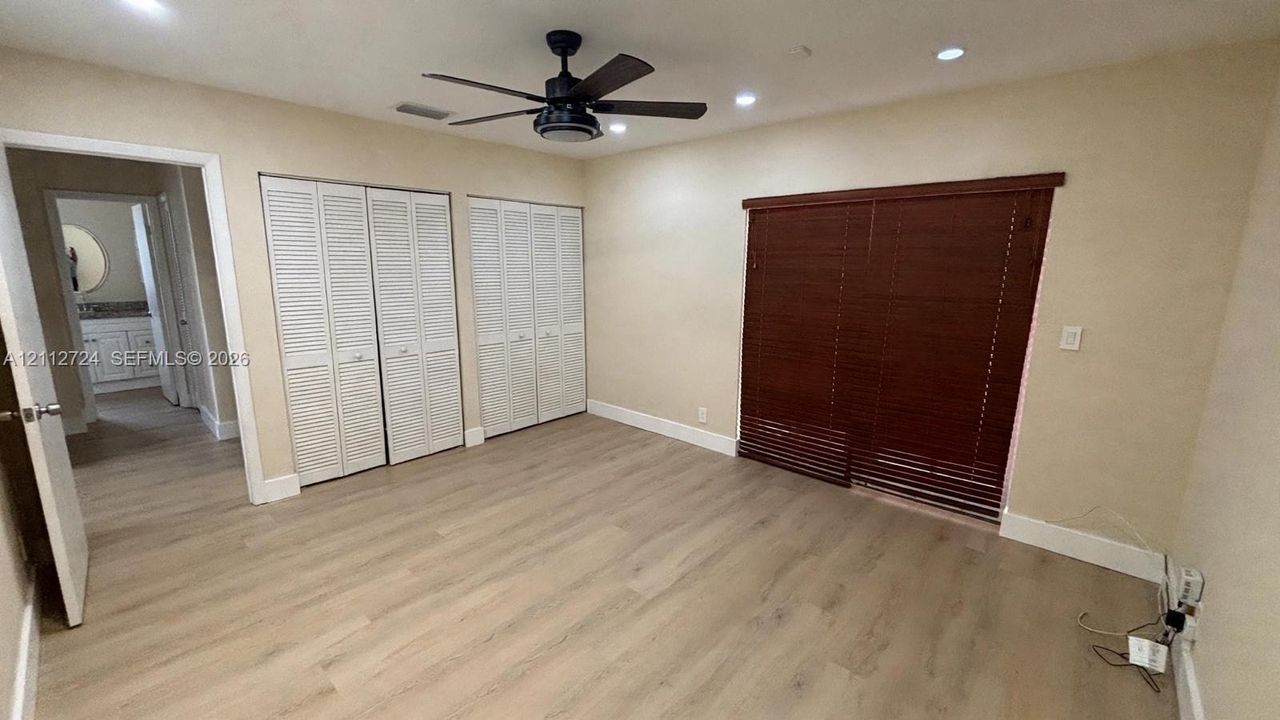 Wood-finish flooring, recessed lighting, ceiling fan with integrated light, double louvered-door closets, and floor-to-ceiling wood blinds