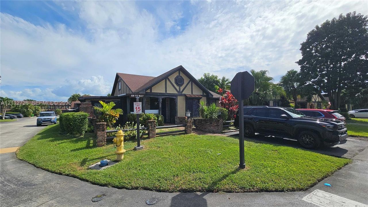 Tudor-style exterior featuring half-timbered accents, stone masonry foundation, a gabled roofline, and landscaped lawn