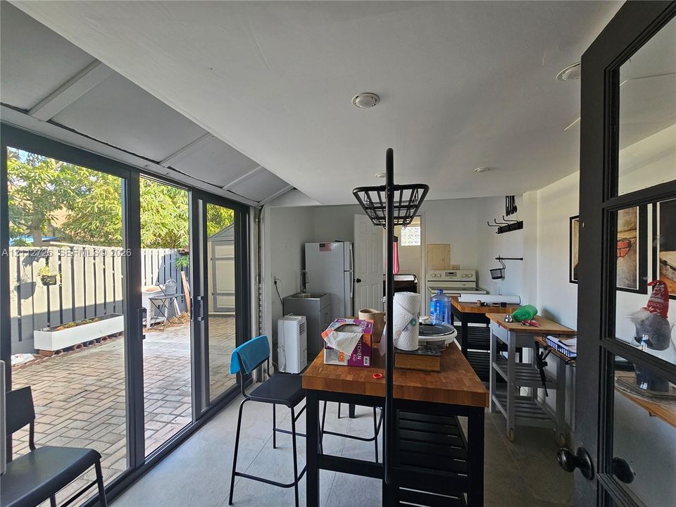 Expansive wall of black-framed glass panel doors opening to a private brick-paved patio