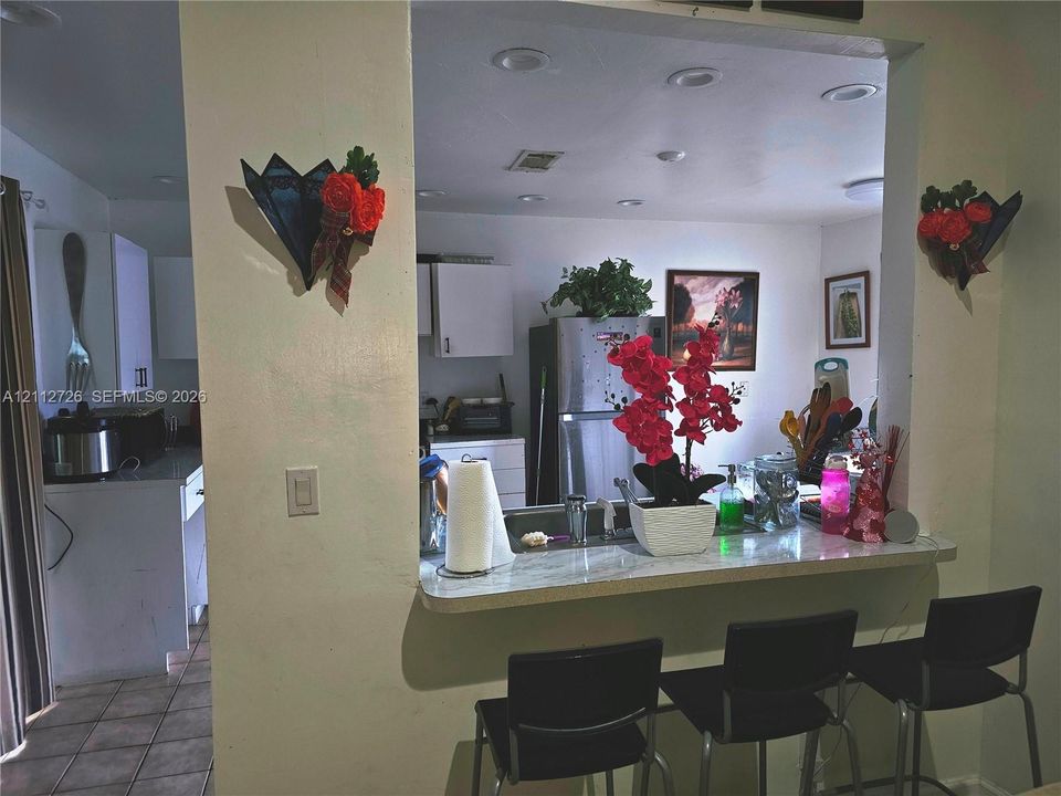 Kitchen featuring white cabinetry, solid-surface countertops, recessed ceiling lighting, and a breakfast bar