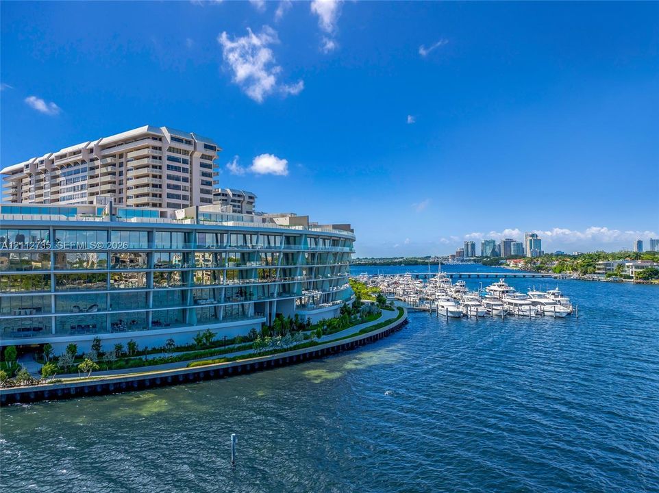 Waterfront mid-rise building featuring glass-railed balconies and a concrete bulkhead, situated directly on the harbor with marina access