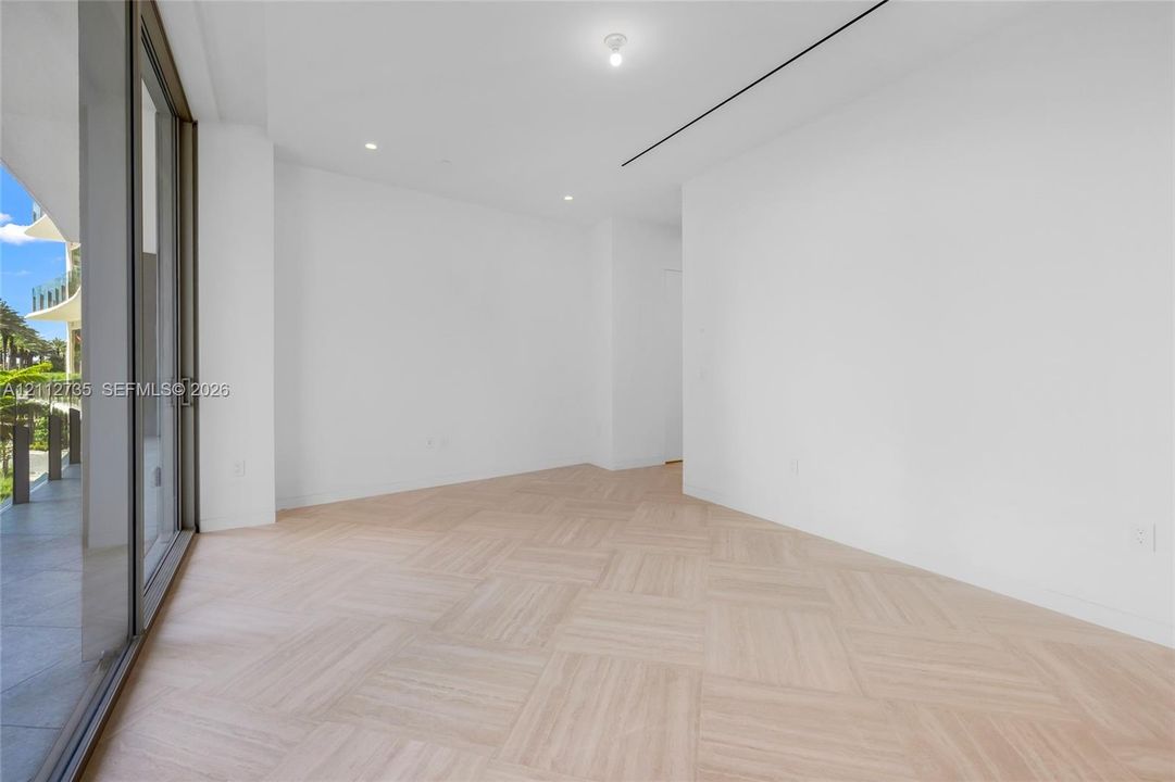 Light-filled interior featuring wood-finish flooring in a basketweave pattern, floor-to-ceiling sliding glass doors, recessed lighting, and linear ceiling detailing